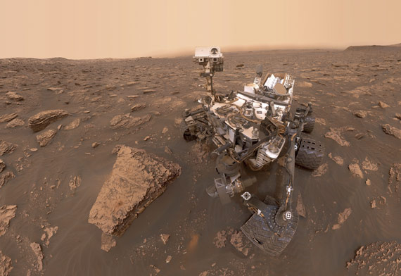 BBVA-OpenMind-ilustración-Martin-Rees-La-ultima-decada-futuro-de-la-cosmologia-y-astrofisica-Autorretrato del robot explorador de la NASA Curiosity, tomado en la jornada Sol 2082 (15 de junio de 2018). Una tormenta de polvo en Marte ha reducido la luz solar y la visibilidad en el cráter Gale, donde se encuentra el robot. En la roca situada a la izquierda de Curiosity se ve un agujero, resultado de la perforación de este en un objetivo llamado Duluth